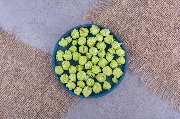 Stukken stof onder een klein dienblad met een portie groene popcorn snoep op marmeren achtergrond. Hoge kwaliteit foto