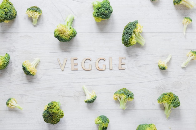 Gratis foto stukken van broccolioregeling met het veggie van letters voorzien op houten lijst