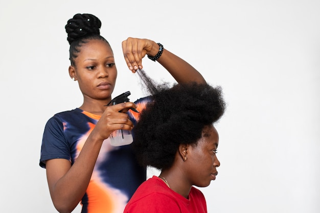 Stylistvrouw die voor haar cliëntafrohaar zorgt