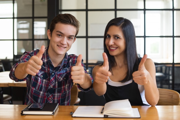 Succesvolle jonge student jongen en meisje duimen opdagen