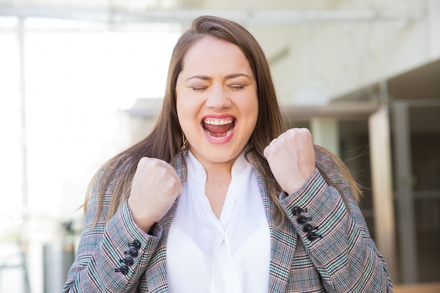 Succesvolle jonge vrouw met opgeheven vuisten