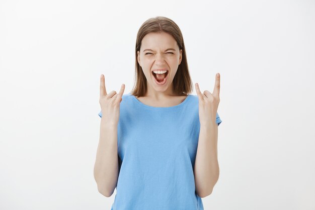 Succesvolle juichende vrouw die van geluk en vreugde schreeuwt, rock-on gebaar toont