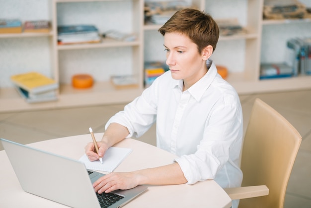 succesvolle werknemer in een helder kantoor is geconcentreerd en schrijft informatie