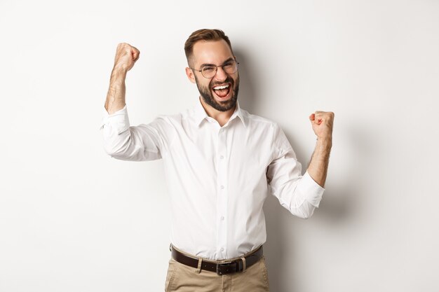 Succesvolle zakenman die zich verheugt, handen opheft en overwinning viert, iets wint