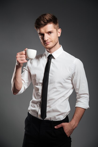 Succesvolle zakenman in formalwear die kop van koffie houden terwijl status
