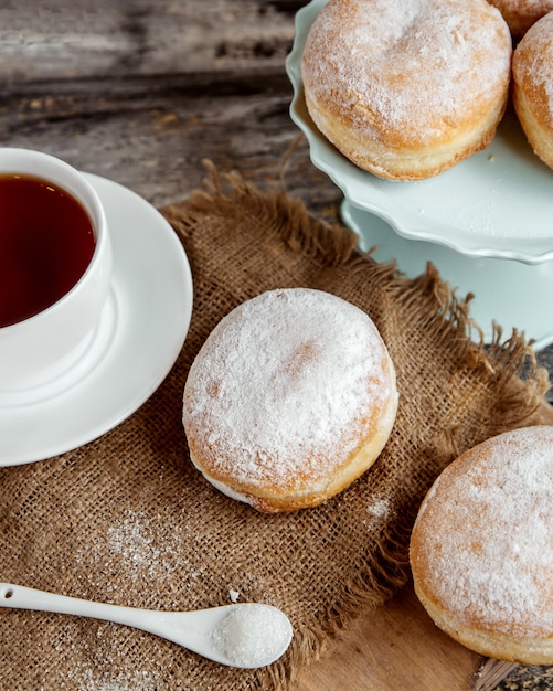 Suiker aangedreven vla donuts geserveerd met zwarte thee