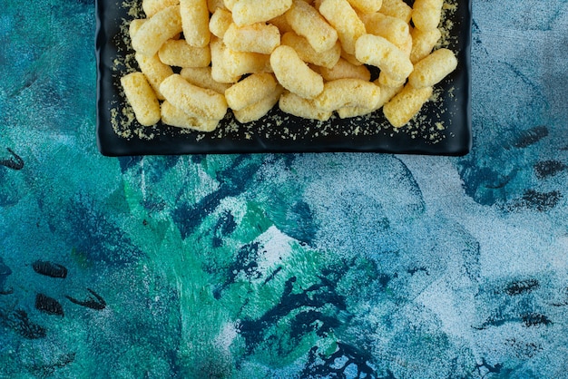 Suikermaïs stokken op een bord, op de blauwe tafel.