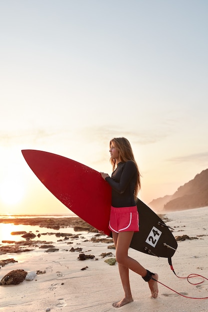 Gratis foto surfboarder met prettige uitstraling draagt board