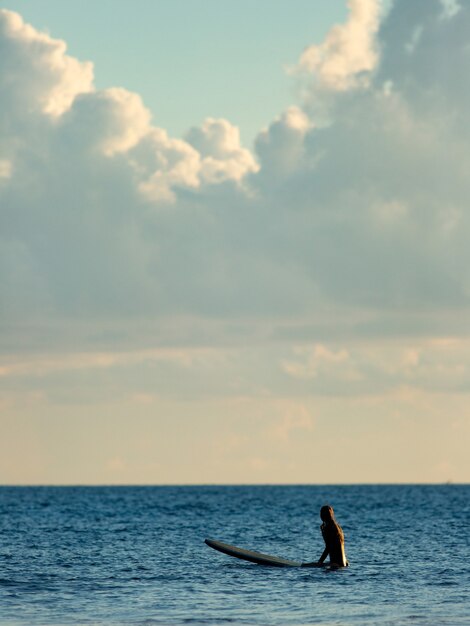 Surfer zittend in de oceaan bij zonsondergang