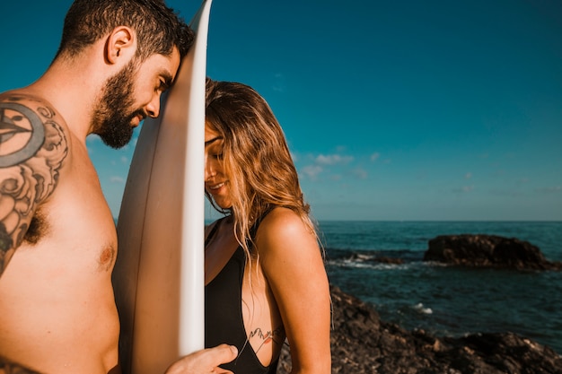 Surfplank tussen jonge vrouw en man dichtbij overzees