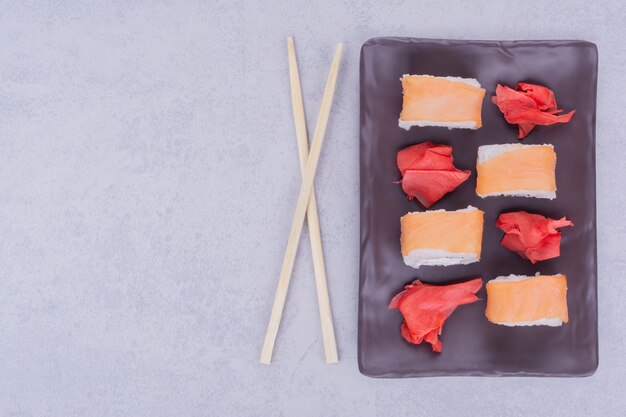 Sushi rolt met zalm in een zwarte keramische schotel.