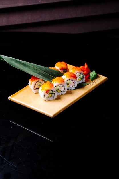 Sushibroodjes met groen blad op een houten bord.