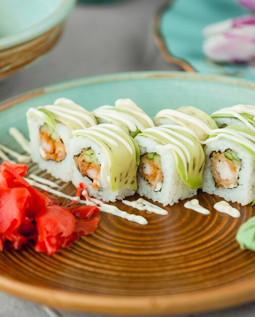 Sushibroodjes met witte saus en rode gember in bruine plaat.