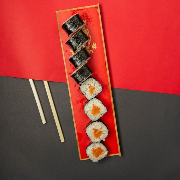 Sushionori in rode schotel met houten eetstokjes.