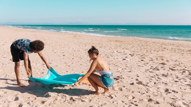 Sweethearts die handdoek op strand uitspreidt