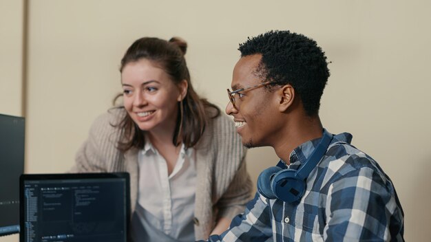 Systeemingenieurs vieren succesvolle codecompilatie en doen een high five handgebaar met collega. Coder die algoritme op meerdere schermen analyseert, zet een bril af en feliciteert de collega.