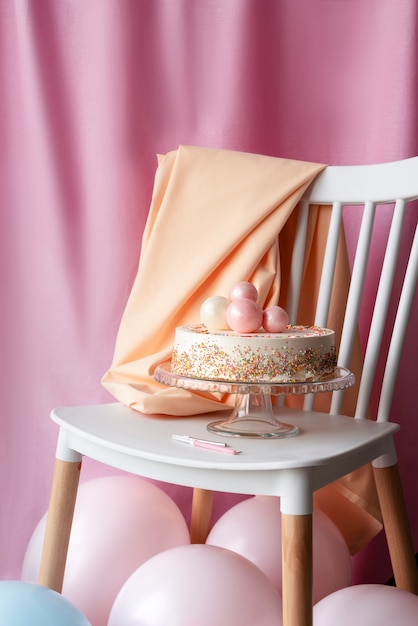 Gratis foto taart voor verjaardagsevenement op stoel met ballonnen