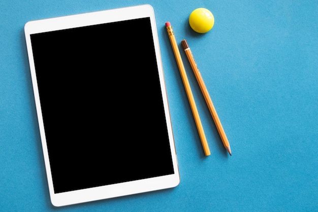 Tablet en potloden op blauwe oppervlak