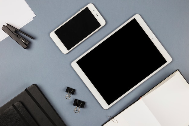 Tablet en smartphone met laptop op grijze tafel