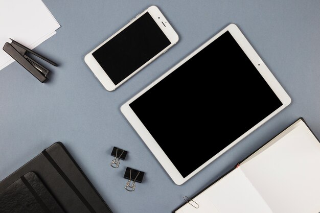 Tablet en smartphone met laptop op grijze tafel