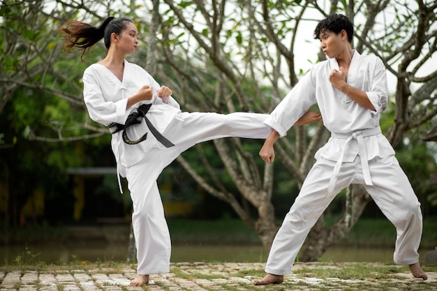 Gratis foto taekwondo training buiten in de natuur met twee personen