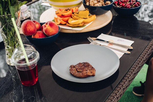 Tafel met smakelijk vers voedsel barbecue vlees op plaat en vers gegrilde groente fruit drank