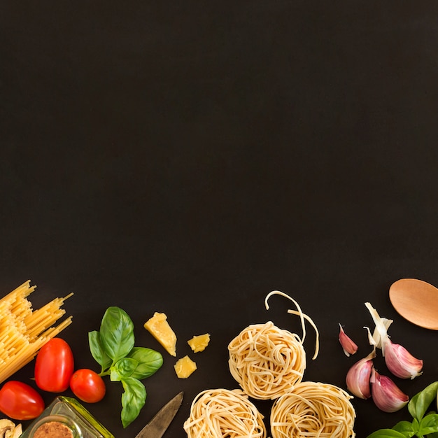 Tagliatelle en spaghettideegwaren met ingrediënten op zwarte achtergrond