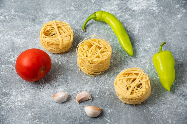 Tagliatelle rauwe pasta nesten en groenten op marmeren tafel.