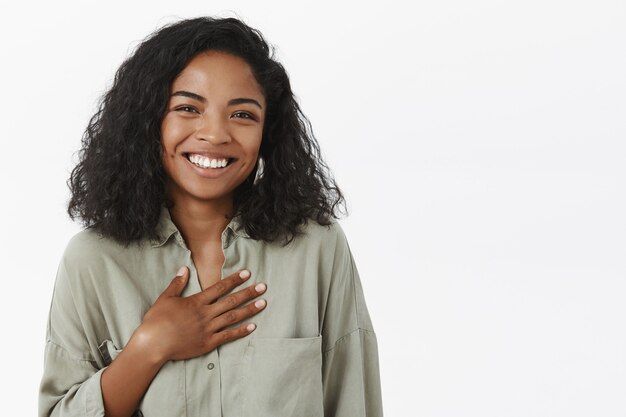 Taille-up shot van geamuseerde aantrekkelijke en stijlvolle jonge Afro-Amerikaanse vrouw met krullend kapsel tevreden