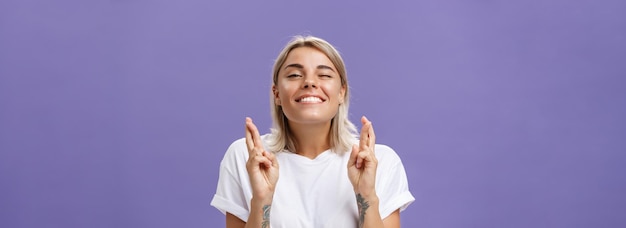 Gratis foto taille-up shot van hoopvolle optimistische aantrekkelijke stijlvolle vrouw in wit t-shirt met getatoeëerde armen winki