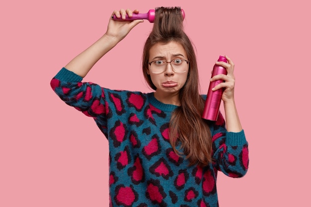 Taille-up shot van ontevreden jonge vrouw met norse uitdrukking, portemonnees onderlip, kapsel zelf maakt, houdt niet van iets