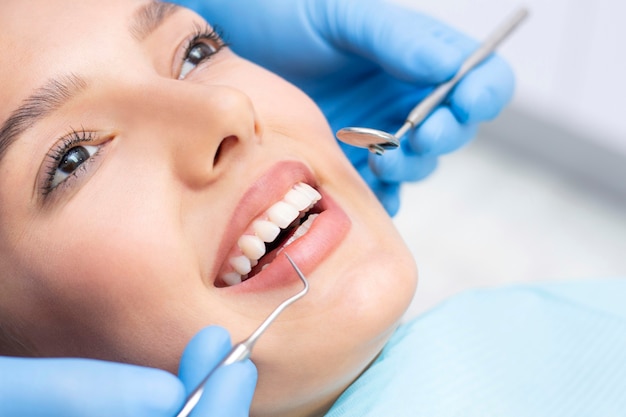 Tandarts en patiënt in de tandartspraktijk. vrouw die tanden laat onderzoeken door tandartsen Premium Foto
