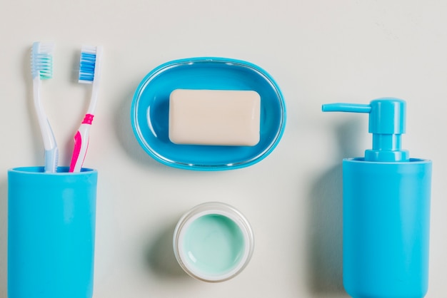 Tandenborstels; room; zeepdispenser en zeep in blauwe container met crème op witte achtergrond