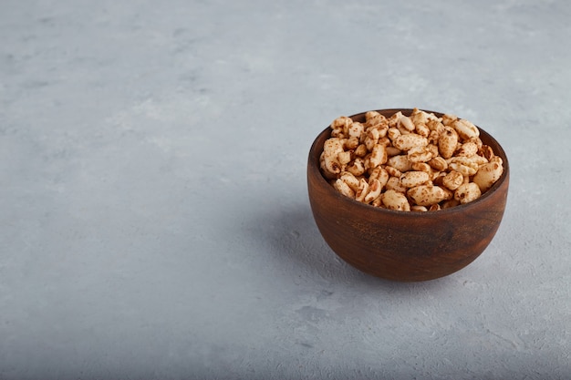 Tarwepopcorns in een houten kom op steenachtergrond.