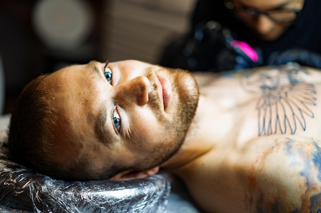 Tattoo salon proces. het proces van het krijgen van een tatoeage op het lichaam, een man in een tattooshop