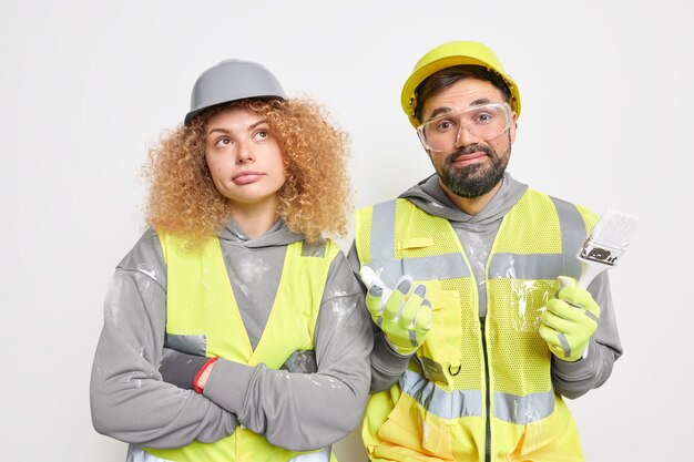 Team van professionele bouwers staat naast elkaar, gekleed in werkuniform, gebruik reparatiegereedschappen, draag veiligheidshelmen, handschoenen, veiligheidsbril