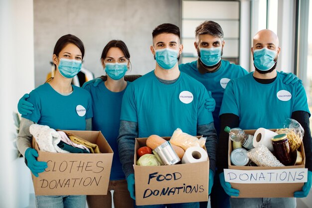 Team van vrijwilligers die donatieboxen vasthouden en naar de camera kijken