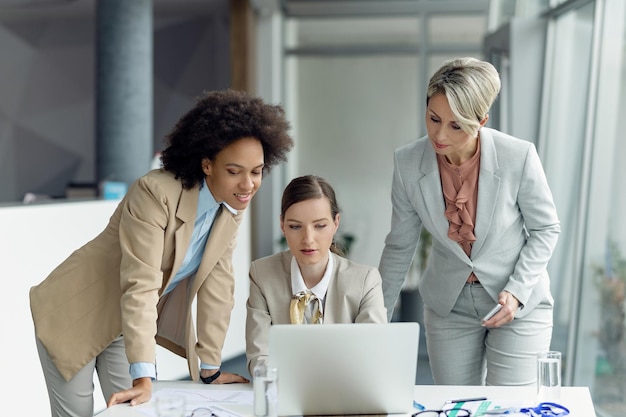 Gratis foto team van vrouwelijke ondernemers die samenwerken tijdens het werken op laptop tijdens zakelijke bijeenkomst