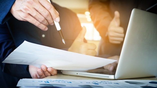 Teamwerkproces. Jonge zakenmanagers die werken met een nieuw opstartproject. Labtop op houten tafel, toetsenbord typen, sms-bericht, grafiekplannen analyseren.