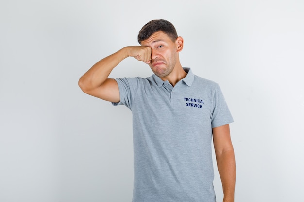 Technische dienst man in grijs t-shirt huilen als een kind en boos kijken