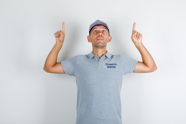Gratis foto technische dienst man in grijs t-shirt met pet die vingers omhoog wijst