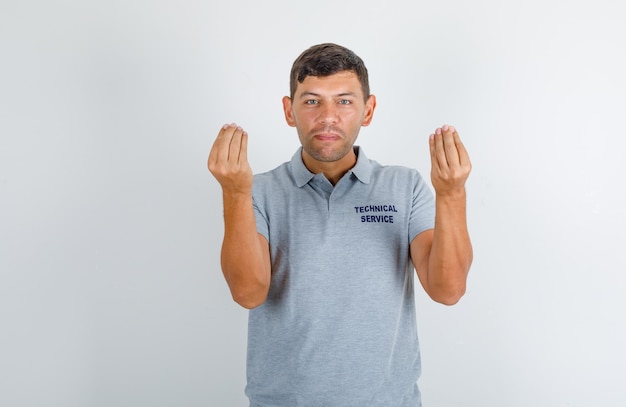 Technische dienst man italiaans gebaar doen met handen in grijs t-shirt en op zoek zelfverzekerd