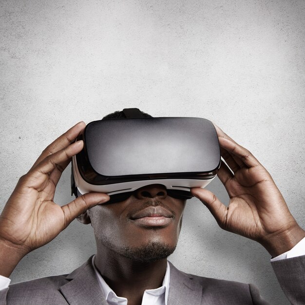 Technologie en entertainment. Afrikaanse kantoormedewerker in formele slijtage, virtual reality ervaren, VR-headset bril dragen.