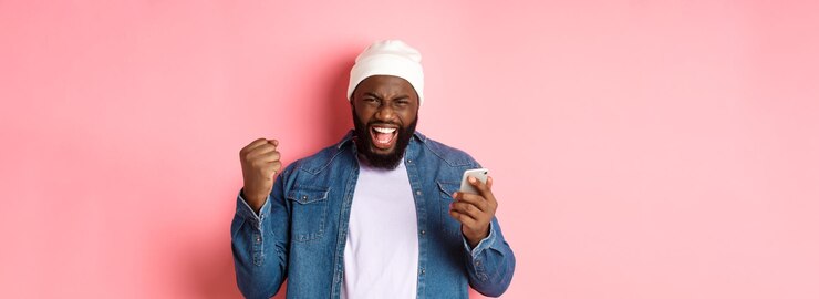 Gratis Foto technologie en online winkelconcept gelukkige zwarte man die zich verheugt over winnen in app met smartphone a