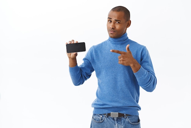 Technologie internet en mensen concept Portret van aantrekkelijke Afro-Amerikaanse man die de bezorgservice van mobiele telefoons promoot of game wijzend op smartphone houdt het horizontaal