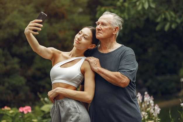 Technologie, mensen en communicatieconcept. Senior man in zomer park. Grangfather met kleindochter.