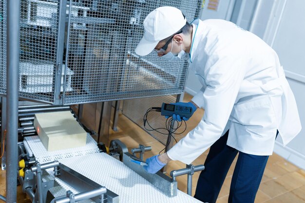 Technoloog maakt het opzetten van de productielijn terwijl hij in de buurt van een digitaal scherm staat op de afdeling zuivelfabriek