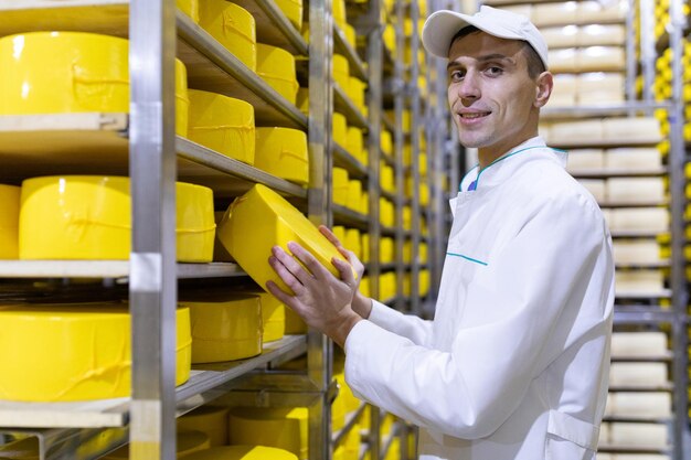 Technoloog met kaas in zijn handen maakt een inspectie van kant-en-klare productie op de afdeling zuivelfabriek