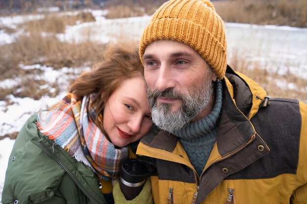 Teder paar van middelbare leeftijd op wintervakantie weg in het wild warm gekleed Glimlachende man en vrouw van middelbare leeftijd in besneeuwde natuur of park samen Familie seizoensgebonden vakantie concept