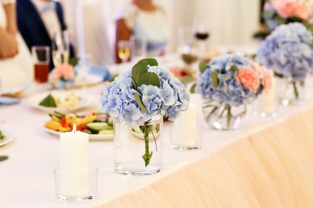 Tedere boeketten van blauwe hortensia&#39;s staan ​​in glazen op tafel